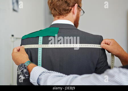Tailor Taking Measurements on Customer Stock Photo