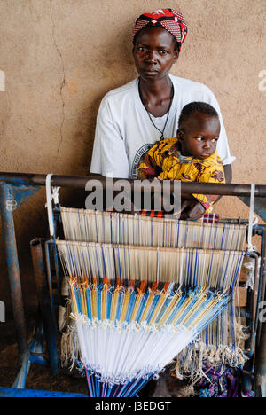 BURKINA FASO, Kaya, aid project of catholic church for forced married women in Boken, textile workshop, vocational training and employment, mother with infant at weaving loom Stock Photo