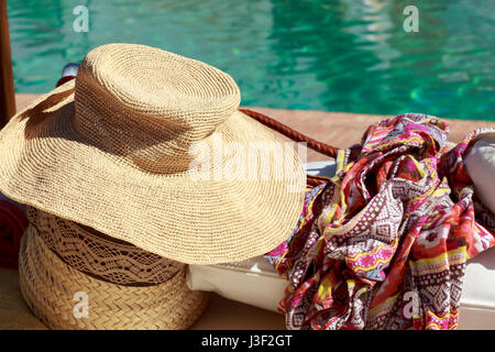 Sun hat and pareo in front of a swimming pool Stock Photo