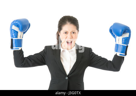 Strong aggressive business woman concept. Businesswoman wearing boxing gloves showing flexing muscles wearing suit. Asian female model isolated on whi Stock Photo