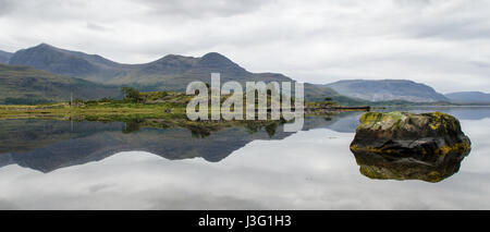 The mountains of Wester Ross in the west Highlands of Scotland are reflected in the calm sea water of Loch Torridon. Stock Photo