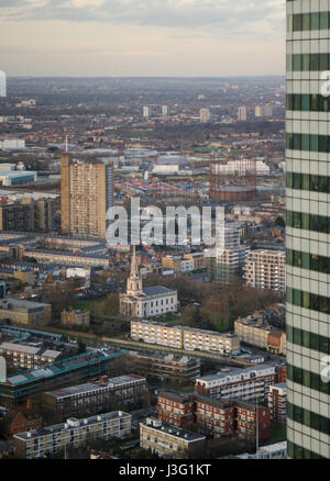 London, England, UK - February 27, 2015: Erno Goldfinger's Balfron Tower council housing apartment building and the Georgian All Saints Church stand p Stock Photo