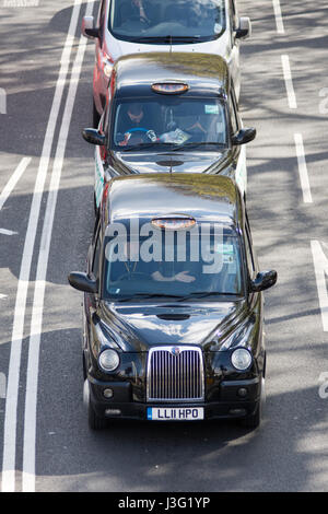 London, England - April 30, 2016: Traditional London taxis queue at traffic signals on London's Embankment road.