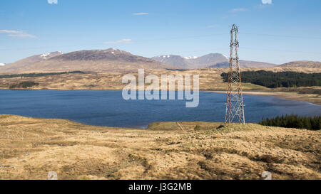 Power lines run alongside Loch Tulla and mountains near Bridge of Orchy and Rannoch Moor in the remote West Highlands of Scotland. Stock Photo