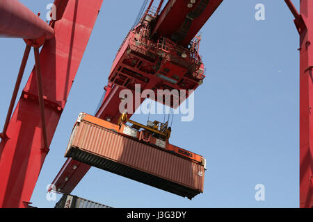 A container being lifted on to a ship by a large crane Stock Photo