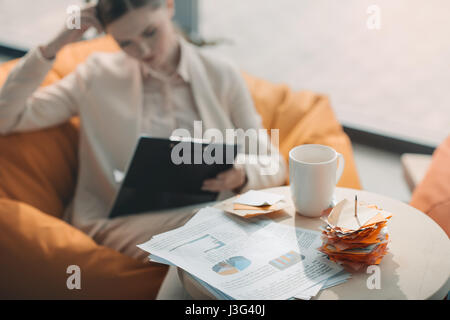 Close-up view of business charts and notes on table and businesswoman working behind Stock Photo
