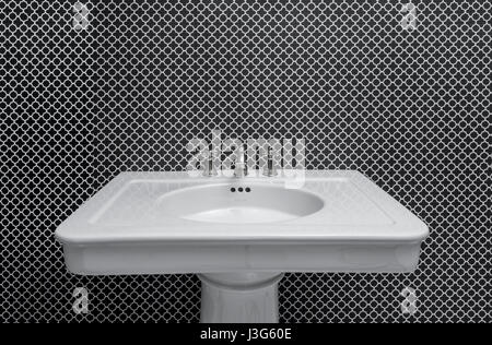 White Pedestal Bathroom Sink With Busy Wallpaper Pattern Stock Photo