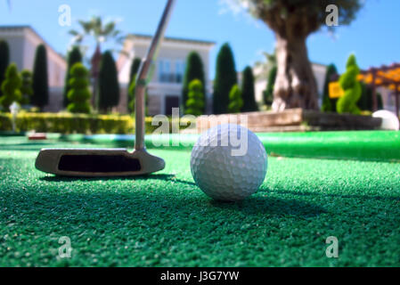 Mini golf scene with ball and club. Sunny day at resort park Stock Photo