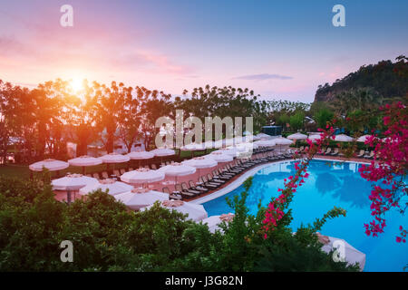 Swimming pool with sunshades and lounge chair in morning time. Amazing scene near mediterranean sea Stock Photo