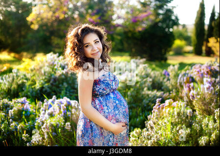 Pregnant woman in the blooming spring garden. Pregnancy and maternity shoot woman. Stock Photo