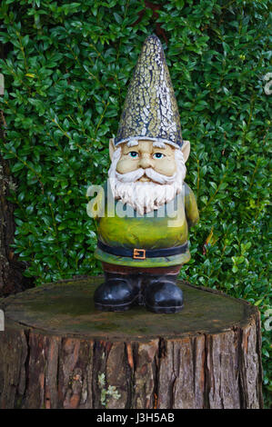 Closeup of Gnome standing on tree stump with sparkled hat and green suit Stock Photo
