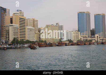 Lots of ships on a sea canal in Dubai. A view at famous skyscrapers from touristic boat. Blocks of flats and office buildings are high, unusual shape. Stock Photo