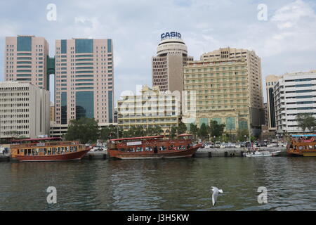 Lots of ships on a sea canal in Dubai. A view at famous skyscrapers from touristic boat. Blocks of flats and office buildings are high, unusual shape. Stock Photo