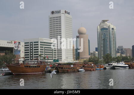 Lots of ships on a sea canal in Dubai. A view at famous skyscrapers from touristic boat. Blocks of flats and office buildings are high, unusual shape. Stock Photo