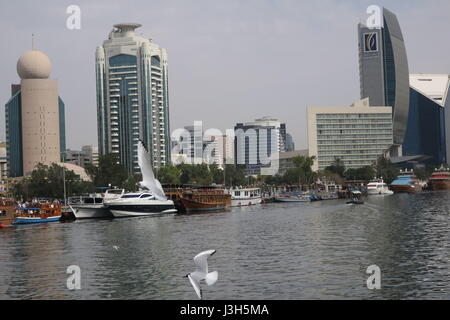 Lots of ships on a sea canal in Dubai. A view at famous skyscrapers from touristic boat. Blocks of flats and office buildings are high, unusual shape. Stock Photo