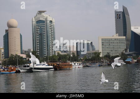 Lots of ships on a sea canal in Dubai. A view at famous skyscrapers from touristic boat. Blocks of flats and office buildings are high, unusual shape. Stock Photo