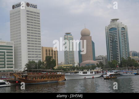 Lots of ships on a sea canal in Dubai. A view at famous skyscrapers from touristic boat. Blocks of flats and office buildings are high, unusual shape. Stock Photo