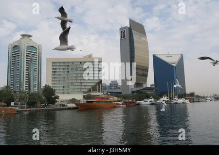 Lots of ships on a sea canal in Dubai. A view at famous skyscrapers from touristic boat. Blocks of flats and office buildings are high, unusual shape. Stock Photo