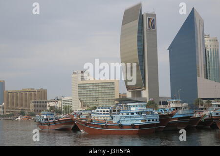 Lots of ships on a sea canal in Dubai. A view at famous skyscrapers from touristic boat. Blocks of flats and office buildings are high, unusual shape. Stock Photo