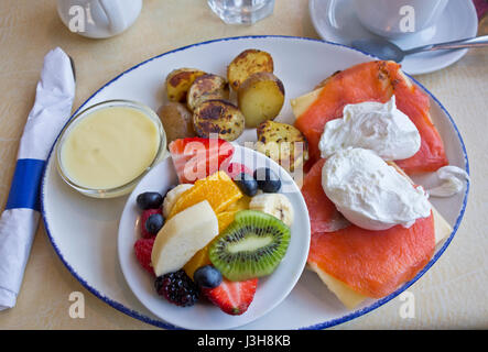 Delicious smoked salmon eggs benedict with fruit and potatoes. Stock Photo