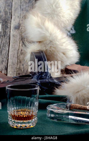 Thompson gun, smoking cigar,  whiskey glass and fur on green cloth and wooden background Stock Photo