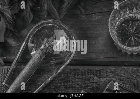 revolver, cigar on ashtray, whiskey glass and blue feather boa Stock Photo
