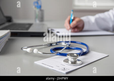 Doctor is filling out report forms after medical examination in his consulting room. Stock Photo