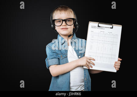 Check yourself. Handsome young male person wearing glasses and headphones with microphone looking straight at camera, standing isolated on black backg Stock Photo