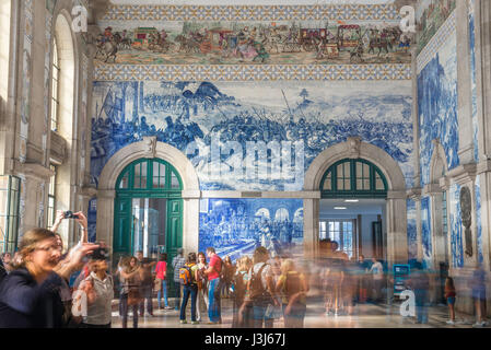 Porto Portugal azulejos, view of the busy entrance hall of the Sao Bento train station decorated with blue azulejo tiles depicting historical scenes. Stock Photo