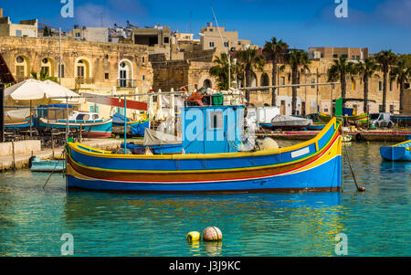 Marsaxlokk, Malta - Traditional colorful maltese Luzzu fisherboat at the old village of Marsaxlokk with turquoise sea water and palm trees on a summer Stock Photo