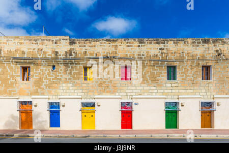 Marsaxlokk, Malta - Traditional maltese vintage house with orange, blue, yellow, red, green and brown doors and windows with blue sky Stock Photo
