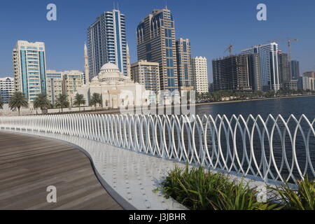 Sharjah is the third largest emirate in the United Arab Emirates. Lots of mighty skyscrapers with glass facades, palm trees, mosques. Nice garden, bay Stock Photo