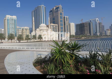 Sharjah is the third largest emirate in the United Arab Emirates. Lots of mighty skyscrapers with glass facades, palm trees, mosques. Nice garden, bay Stock Photo