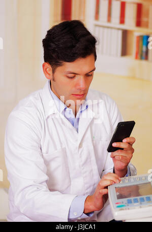 closeup shot young male technician testing digital photocopier machine while he is using his celphone. Stock Photo