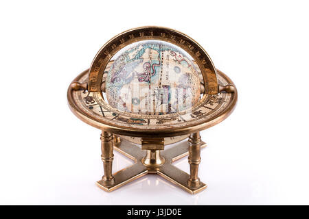 Vintage world globe on a brass stand on a white surface. Antique world globe isolated on white background. Stock Photo
