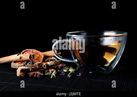Warming spices and tea infusion on bamboo mat - cinnamon sticks, cardamom, cloves, bael fruit, juniper berries and star anise Stock Photo