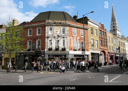 People outside Truman's pub The Golden Heart on the corner of busy Commercial St and Hanbury Street Commercial Road East London E1  KATHY DEWITT Stock Photo