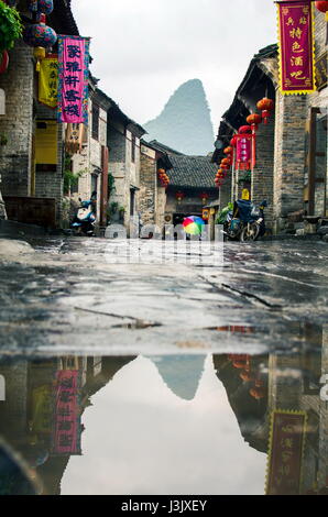 HUZHOU, CHINA - MAY 3, 2017: Huang Yao Ancient Town street in Zhaoping county, Guangxi province. Karst formation reflected in the rain water Stock Photo