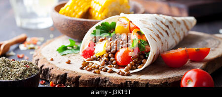 Vegan tortilla wrap, roll with grilled vegetables and lentil wooden background Stock Photo