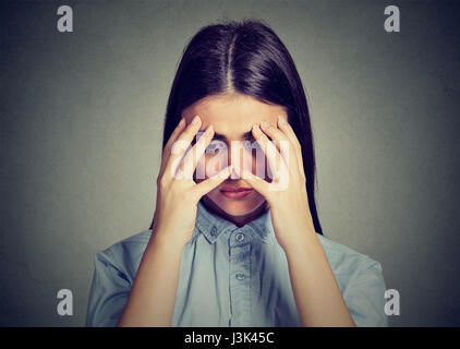 Closeup depressed sad woman looking down leaning head on hands isolated on gray background Stock Photo