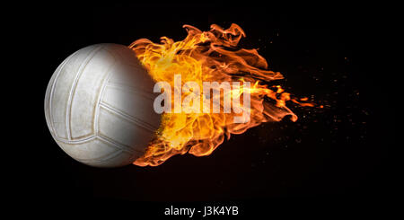 Flying volleyball engulfed in trailing flames with sparks flying on a black background. Concept of a fiery competition or fast moving ball. Stock Photo
