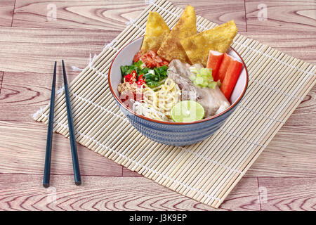 Japanese noodle (ramen) in spicy soup as 'tom yam ' topped steamed streaky pork,wonton,green lemon,crab stick,dried shrimp,bean sprouts,roast nut and  Stock Photo