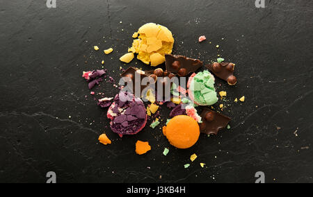 Crumbs of sweet macarons on a black stone table Stock Photo