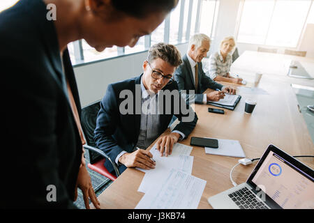 Mature business man discussing over documents during meeting in conference room. Corporate professionals having a meeting. Stock Photo