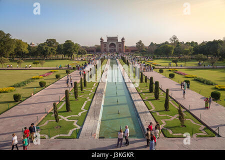 Taj Mahal garden with tourists and red sandstone built Mughal architectural East gate as viewed from the top of the mausoleum. Stock Photo