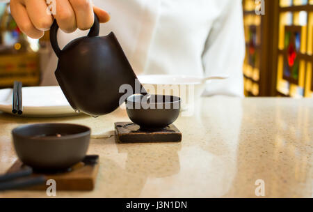 Female pouring tea into ceramic teacup in Chinese restaurant Stock Photo