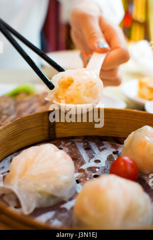 Girl taking shrimp dumpling with chopsticks in a restaurant Stock Photo