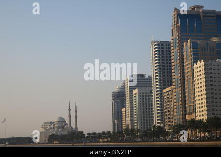 Sharjah is the third largest emirate in the United Arab Emirates. Lots of mighty skyscrapers with glass facades, palm trees, mosques. Nice garden, bay Stock Photo