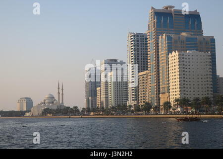 Sharjah is the third largest emirate in the United Arab Emirates. Lots of mighty skyscrapers with glass facades, palm trees, mosques. Nice garden, bay Stock Photo