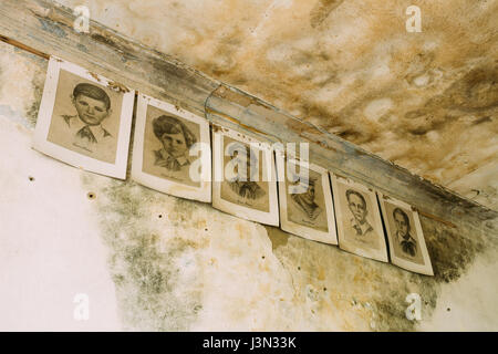 Close Six Black And White Paper Portraits Of Young Pioneers, Heroes Of WW2 War On Cracked Wall Of Classroom In Abandoned School After Chernobyl Nuclea Stock Photo